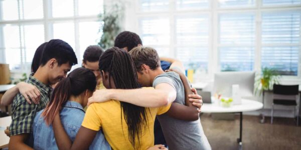 Group of happy business executives forming huddle in office