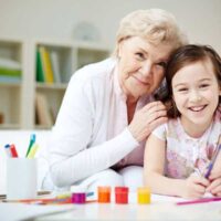 Portrait of happy girl and her grandmother looking at camera at home