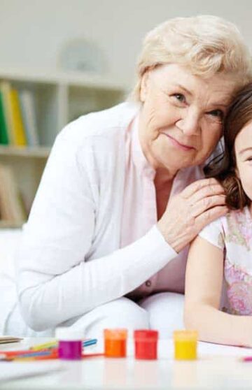 Portrait of happy girl and her grandmother looking at camera at home