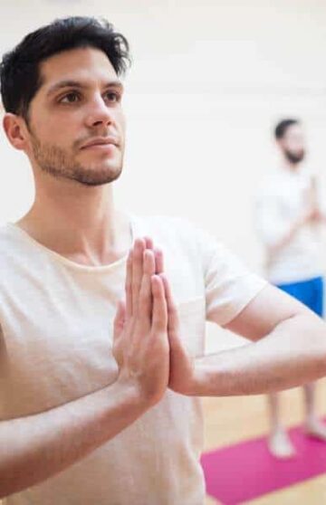 Group of people performing tree-pose yoga exercise in the fitness studio