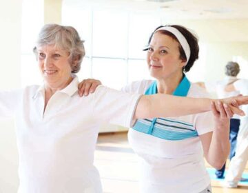 Portrait of sporty female supporting her friend while doing physical exercise in sport gym